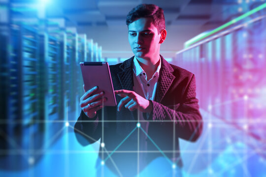 Data analyst monitors digital infrastructure using tablet in modern server room. Network management and cybersecurity operations in IT environment.
