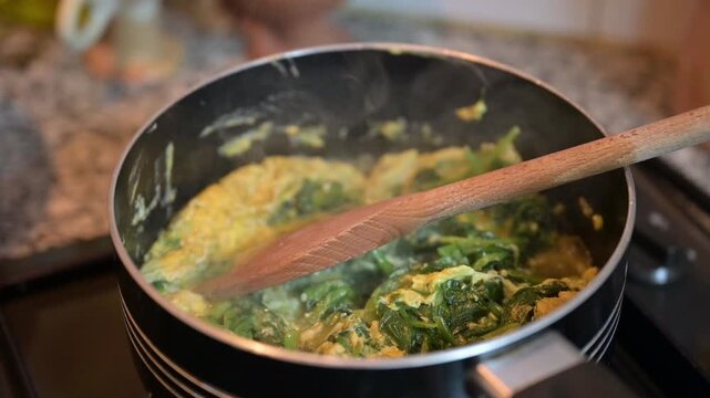 The Cooking scrambled eggs with spinach in a pan