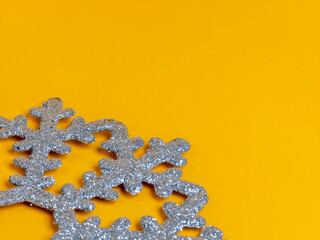 A snowflake made of glitter sits on a yellow background