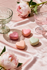 Tennis party setting with heart-shaped macarons and refreshing drinks on soft pink fabric amidst beautiful peonies