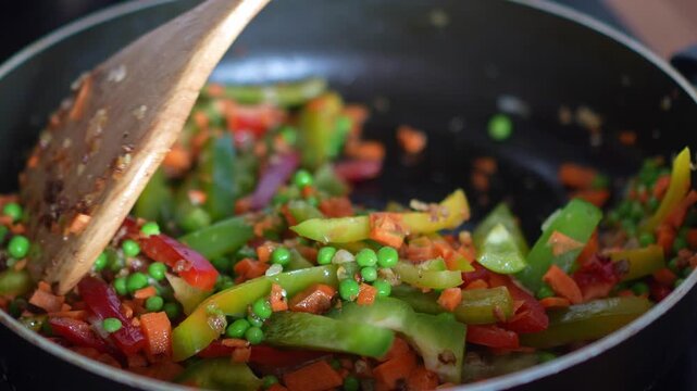 Freshly Cut Bell Pepper, Green Chili, Carrot and Peas Being Stir-Fried in a Pan