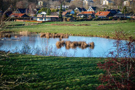 A serene landscape photograph showcasing a beautiful lake view in a peaceful Danish village, surrounded by nature and soft light.