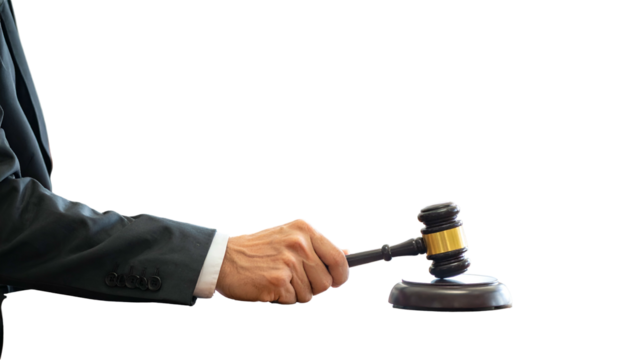 A person in a suit holds a wooden gavel. The background is black
