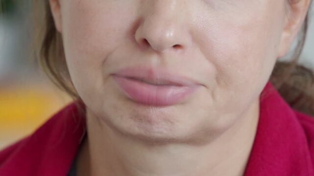 Human mouth and face. A woman blows air out through her closed lips to create a rattling sound. The resulting noise is a wet, sputtering, and rattling sound.