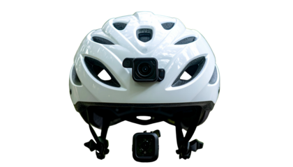 A white bicycle helmet with two action cameras attached. Black background. Front view