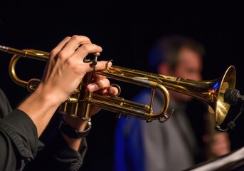 Obraz premium Close-up view of musician's hands playing a shiny brass trumpet during a live performance