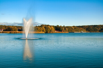 Barlinek (niem. Berlinchen) – Wysoka fontanna tryska z spokojnego jeziora, rozpryskując mgiełkę w jasnoniebieskie niebo. © Pol Badger
