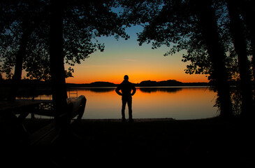 Barlinek (niem. Berlinchen) – Samotna sylwetka stoi na pomoście, patrząc na rozświetlony zachód słońca nad spokojnym jeziorem. © Pol Badger