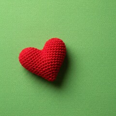 Obraz premium Cozy handmade red knit heart resting on a vibrant, textured green fabric backdrop, symbolizing love, affection, comfort, and craft ,soft ,craft ,heart