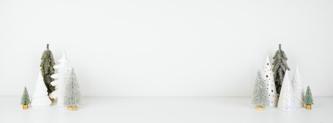 Green and white Christmas tree decor on a white shelf against a white wall banner background with...