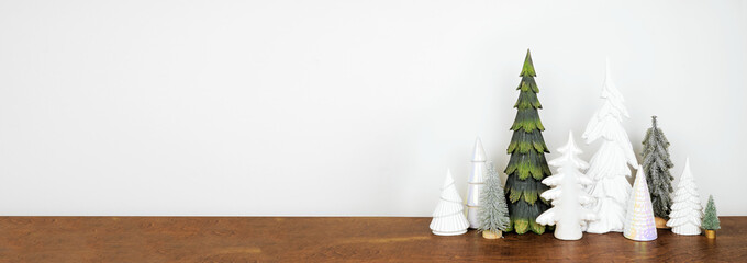 Green and white Christmas tree decor on a wood shelf against a white wall banner background with copy space