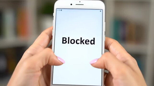 Close up of a woman's hands gripped around a mobile phone displaying a message that says Access Denied. She appears frustrated as she struggles to use her device but is unable to view any content