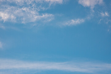 Fototapeta premium Expansive blue sky with soft white clouds, creating a serene atmosphere, ideal for backgrounds, design projects, and conveying a sense of tranquility and openness