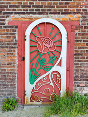 Romantic wrought iron door with rose on brick wall