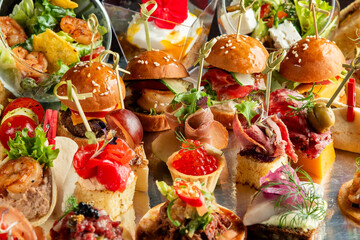 A vibrant, close-up photo of various gourmet appetizers & mini burgers on a catering buffet table, perfect for event, party, or food concepts.