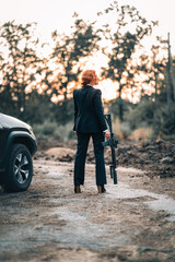 Redhead woman in a suit with a rifle