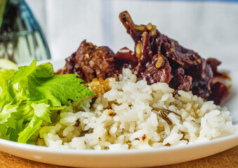 A delicious meal of savory, saucy meat (teriyaki) served with rice and a fresh celery garnish