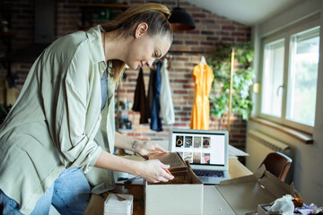 Young adult woman focused packing order in home studio