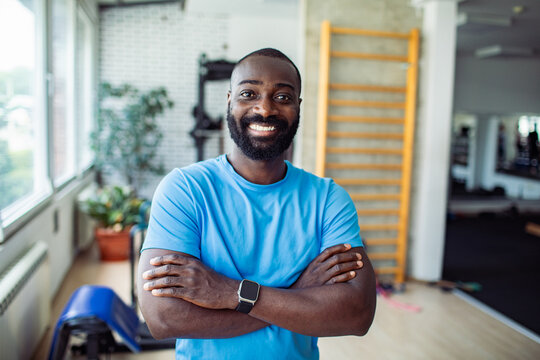 Confident adult man smiling with arms crossed in gym
