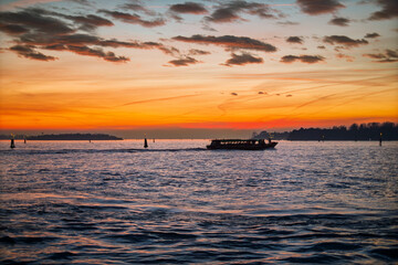 Backlight of a vaporetto at sunset. A vaporetto, in backlight, crosses the lagoon in a golden sunset on an autumn evening. Venice, Italy