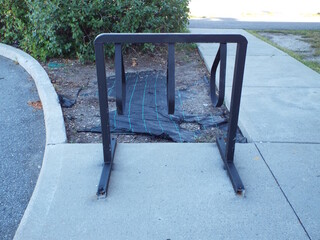 An empty, black metal bicycle rack installed on a concrete sidewalk.