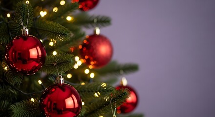 Closeup of a christmas tree decorated with red baubles and warm lights against a purple background