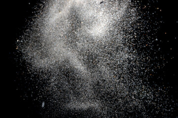 White dust particles explosion on black background