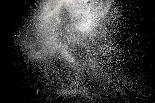 White dust particles explosion on black background