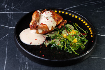 Roasted Chicken Leg Plate with Fresh Greens and Sauces on Dark Marble