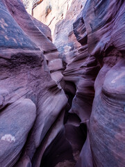 Narrow sandstone passage with sculpted walls and a natural arch in Peekaboo Canyon