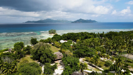 Luxury resort photo of Seychelles tropical paradise islands
in Indian Ocean with palm trees, sandy beach, mountain. Beautiful photography, coral reef, azure ocean, 
sky with clouds on horizon.  