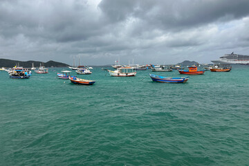 A peaceful coastal harbor filled with small wooden fishing boats gently floating on clear, turquoise water. Búzios bay Brazil