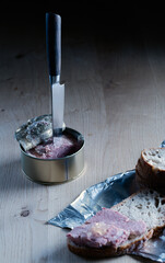 ose-up of an open metal tin of with spam knife stuck in it, next to slices of bread. Simple and minimal meal concept
