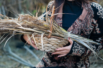 una donna tiene in braccio un cesto con canne in autunno