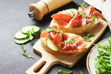 Appetizer crostini, open sandwiches with cream cheese, prosciutto, cucumber and arugula.
