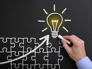Drawing light bulb on blackboard, Steps shaped jigsaw puzzle. Concept image of developing new idea