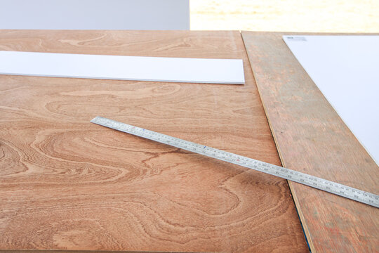 Ruler is on a wooden table next to a piece of paper