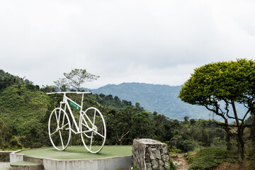 A bicycle on a raised platform, overlooking a lush, green, mountainous landscape in Constanza, Dominican Republic