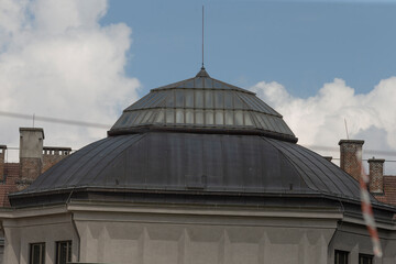 circular dome roof framed by clouds and soft blue sky, weathered metal patina and subtle rooftop details