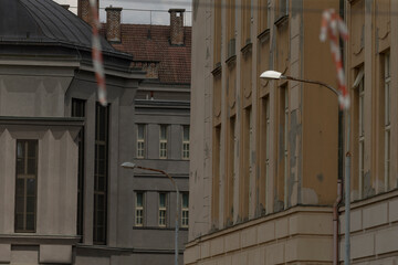 moody narrow european street between facades, lamp and red striped tape signal maintenance, muted ochre