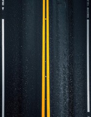 Aerial view of a wet, dark road with double yellow lines