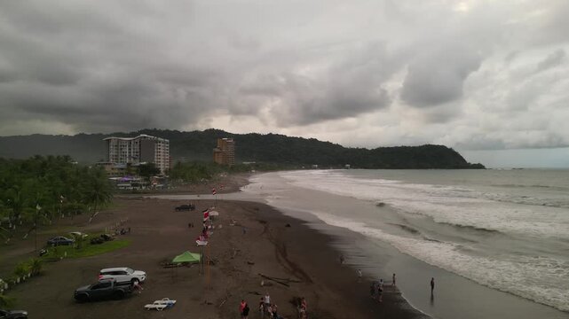 Aerial view of the coastline with waves at sunset near the beach town of Jaco with tourist and hotel buildings and businesses in Puntarenas in Costa Rica