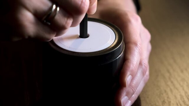 Female hand sticking pencil into automatic electric pencil sharpener and sharpening it close-up side view. Office stationery tool. Preparation for drawing and sketching. High quality 4k footage.