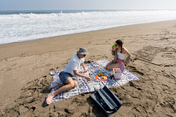 Young couple enjoying beach picnic on clear day
