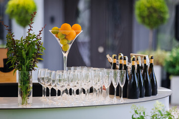 Outdoor champagne bar with citrus centerpiece, glass flutes and bottles ready for service