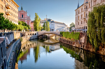 Ljubljana, Slovenia – July 14, 2025: A scenic view of the Ljubljanica River as it winds through the historic center of Ljubljana. Lined with trees, cafés, and charming riverside architecture.
