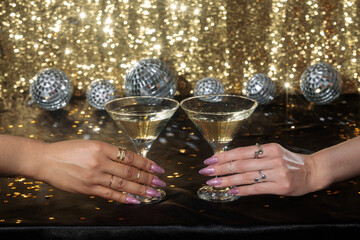 hands with champagne glasses, hands holding glasses on the black table and on a shiny gold...