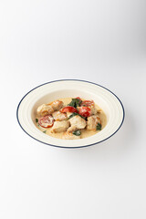 Creamy chicken with cherry tomatoes and spinach in a bowl on white background