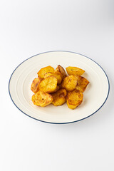 Golden roasted potato chunks on a plate, crispy and seasoned, isolated on white