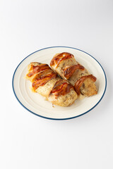Hasselback chicken breasts baked with tomato and melted cheese on a plate, isolated